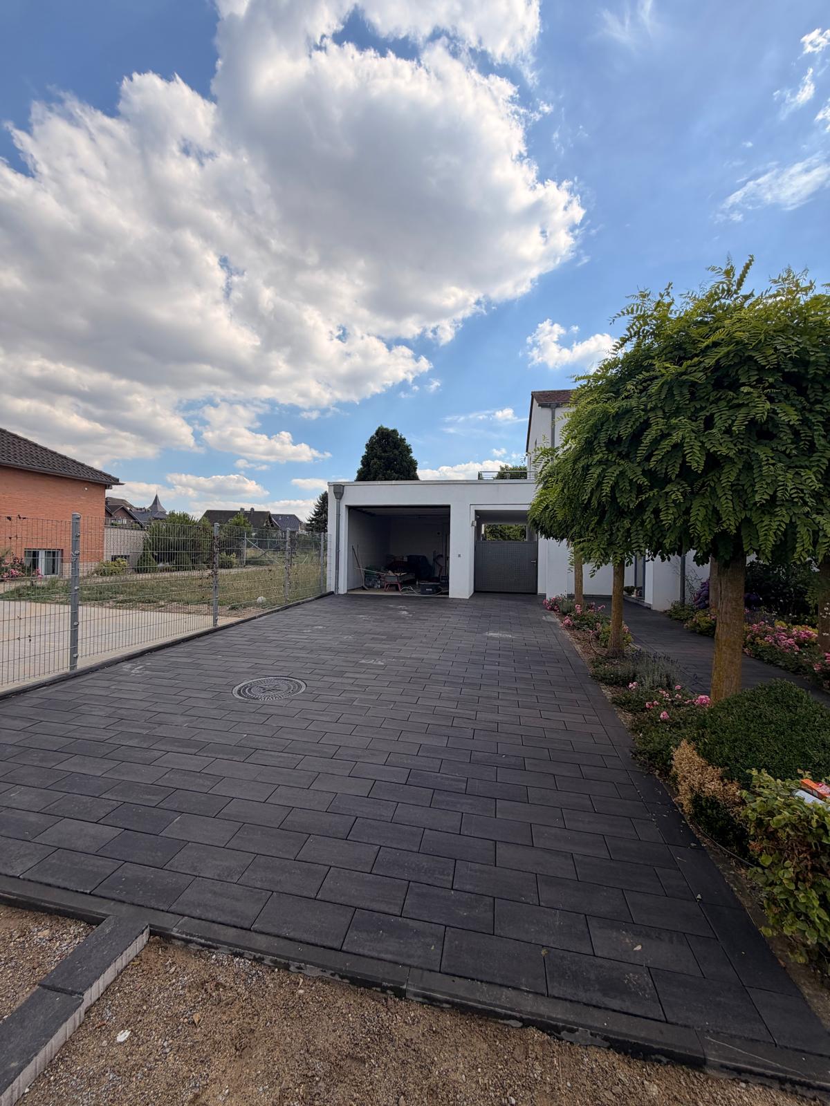 Gepflasterte Einfahrt mit Carport, dunkles Pflaster